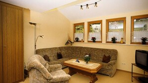 A living room with a sectional sofa, a coffee table, a television, and a lamp. - Apartment 'Margot Armbruster' with Mountain View, Balcony and Wi-Fi (Bad Rippoldsau-Schapbach)