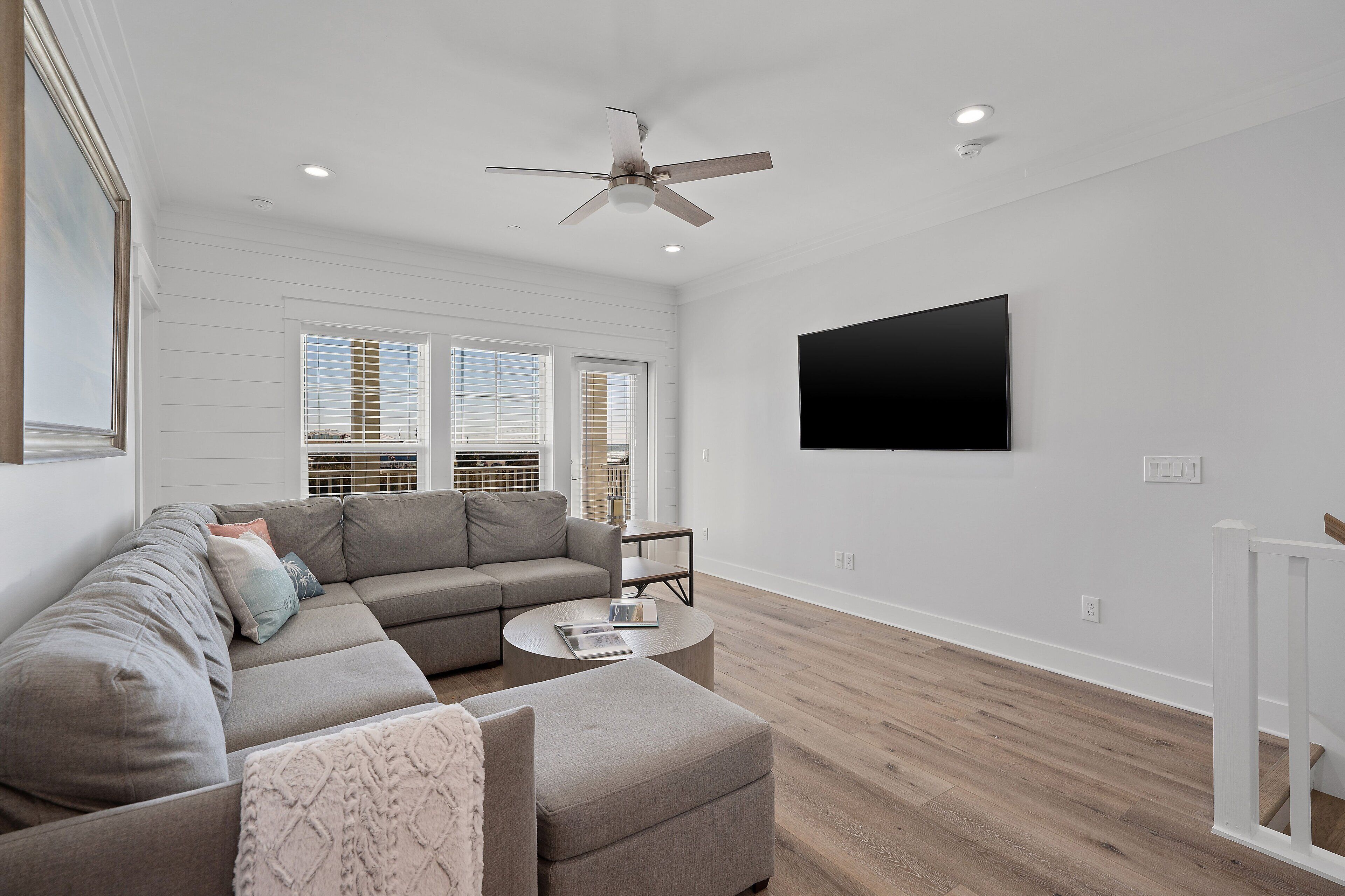 A modern living room with a sectional sofa, a round coffee table, and a ceiling fan.