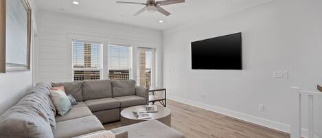 A modern living room with a sectional sofa, a round coffee table, and a ceiling fan.