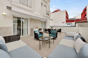 A modern outdoor seating area with sofas, chairs, and a table, featuring a view of the cityscape. - Seashell Diamond Luxury Suite (Playa San Juan)