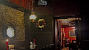 A dimly lit bar area with wooden furniture, a stone wall, and a life preserver decoration. - Parkhotel Essen (Essen)