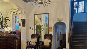 A spacious living room with a large patterned rug, a chandelier, and a staircase leading to another level. - Parkhotel Essen (Essen)
