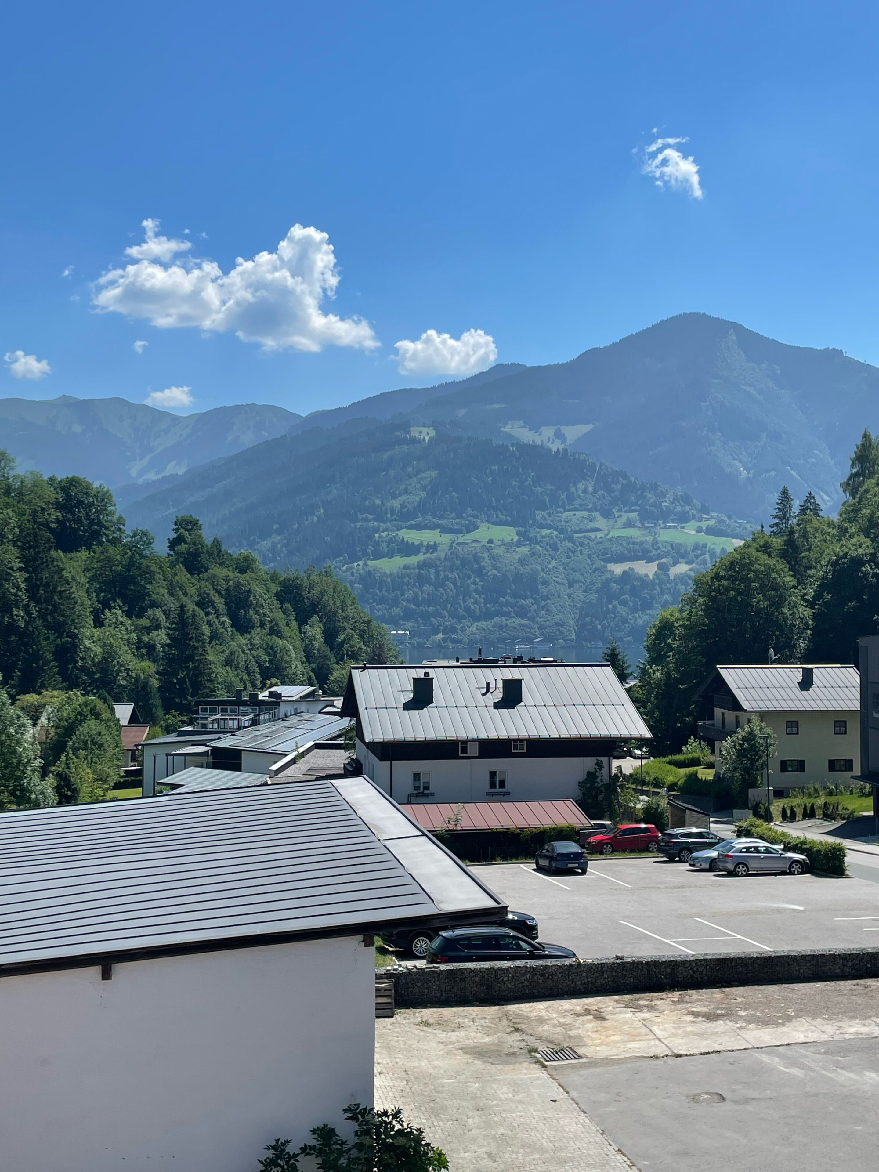 A residential area with houses, a parking lot, and mountains in the background.