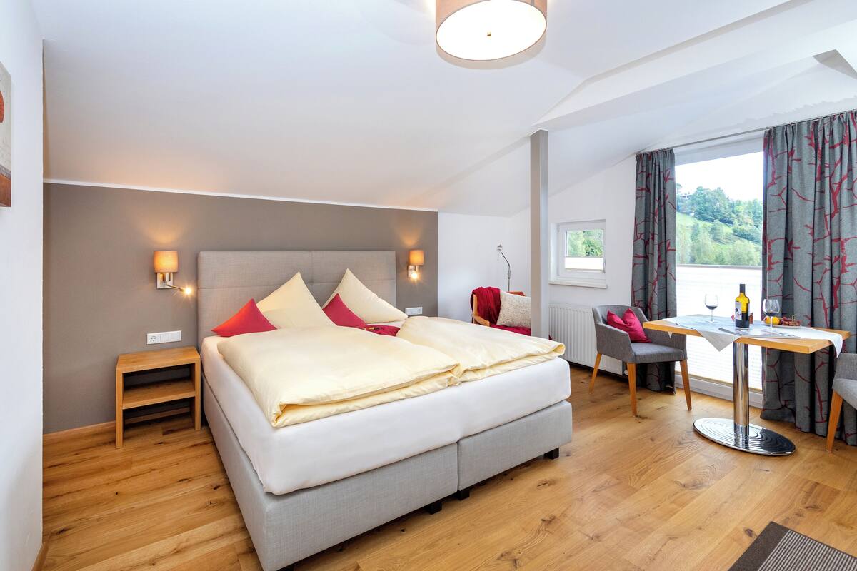 Una habitación de hotel moderna con una cama grande, un escritorio y vistas al exterior.