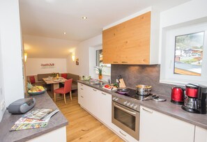 A modern kitchen with wooden cabinets, a built-in oven, and a coffee maker. - Schwaiger Appartements Zell am See (Zell am See)