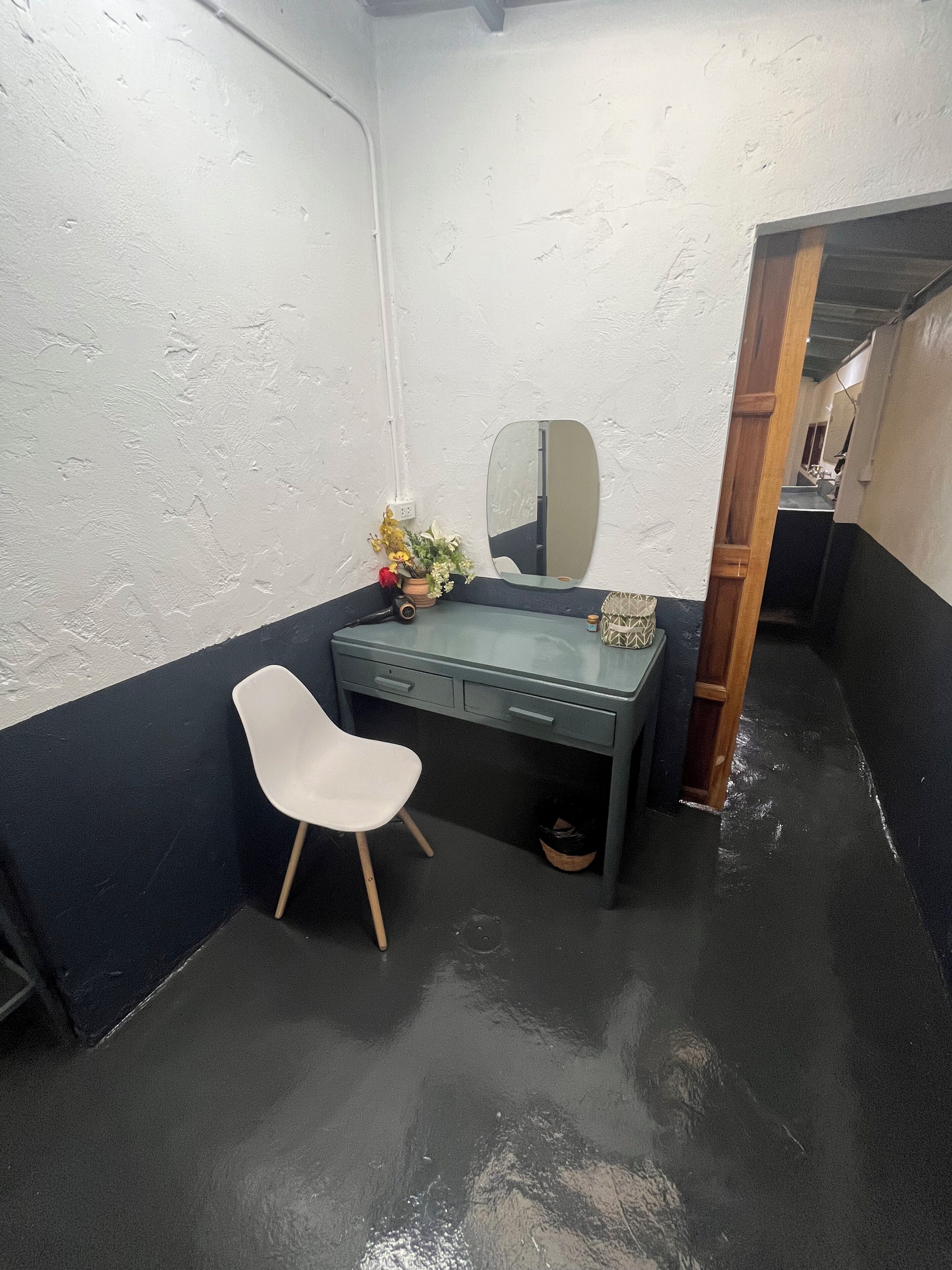 Une petite pièce étroite, avec un bureau, une chaise, un miroir et une plante en pot.