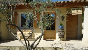 A building with a wooden door, a bench, and a potted plant in the foreground. - Winery Cottage on a Vineyard Estate, Pellerin (Montbrison sur Lez)