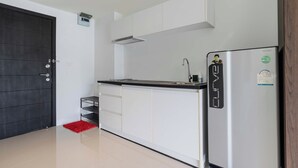 A modern kitchen with white cabinets, a stainless steel refrigerator, and a black countertop.