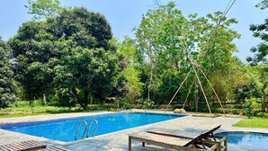 Una piscina con tumbonas de madera y un pequeño puente.