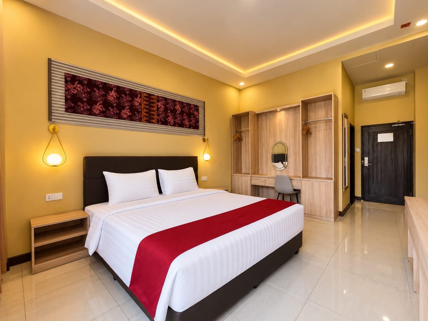 Una camera d'albergo con un letto grande, comodini, una scrivania con sedia, un armadio e uno specchio.