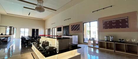 Un hall d’hôtel spacieux, doté d’un comptoir central, de grandes fenêtres et d’un plafond haut orné d’un lustre.