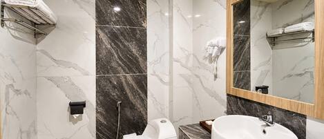 A modern bathroom with a marble wall, a toilet, a sink, and a mirror.