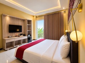 Habitación de hotel con cama, televisión, escritorio con computadora, minibar y balcón con cortinas.