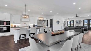 Una cocina moderna con armarios blancos, una isla central e iluminación colgante.