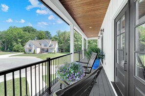 Ein überdachter Balkon mit einer Bank, einem Blumentopf und Blick auf ein Haus.