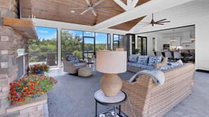 Una sala moderna con chimenea de piedra, muebles de mimbre y un ventanal con vistas al exterior.