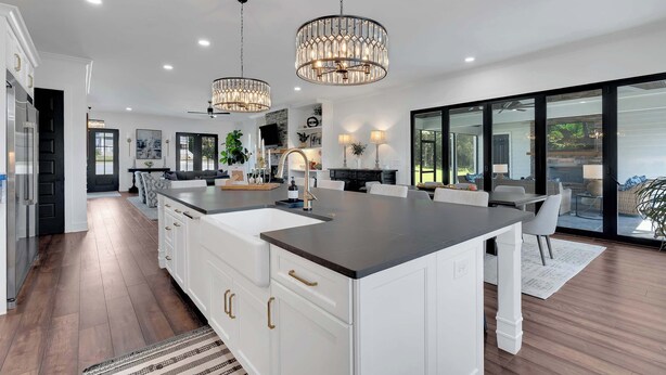 Una cocina moderna con armarios blancos, una isla grande e iluminación colgante.