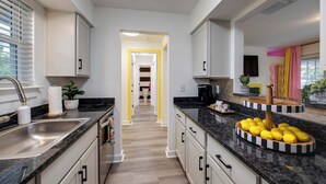 A modern kitchen with white cabinets, a granite countertop, and a central island with lemons.