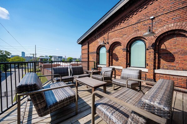 A balcony with wicker furniture and a brick building in the background.