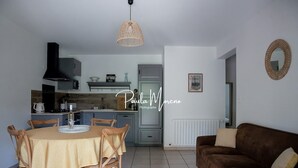 Een moderne keuken met een eettafel en stoelen, een bruine bank en een hanglamp.