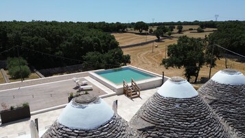 Una piscina en la azotea con borde de piedra, una pared de piedra y vistas al campo circundante.