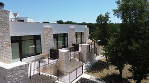Un edificio moderno con paredes de piedra, ventanas grandes y un balcón con barandilla de metal.