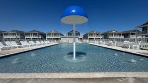 A swimming pool with lounge chairs and a large blue water feature in the center. - Salt & Stone Villa 3425 (Galveston)