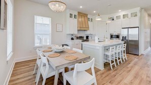 A modern kitchen with white cabinetry, a central island with seating, and a chandelier. - Salt & Stone Villa 3425 (Galveston)