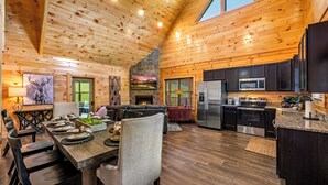 A spacious log cabin interior with a dining area, living room, and kitchen. - Luxe Cabin • Pool • Hot Tub • Games • Pet Friendly (Pigeon Forge)