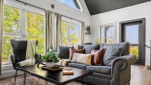 Un salon moderne avec un canapé gris, un fauteuil noir et une table basse en bois.