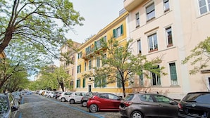 Una fila de coches aparcados en una calle empedrada bordeada de edificios de varios pisos.
