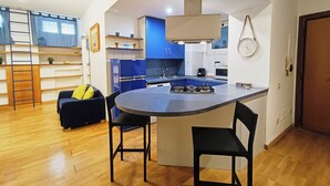 Una cocina compacta con isla central, electrodomésticos integrados y un comedor con sofá y sillas.