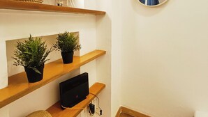 Un interior moderno con estanterías de madera, un televisor de pantalla plana, plantas en macetas y un espejo montado en la pared.