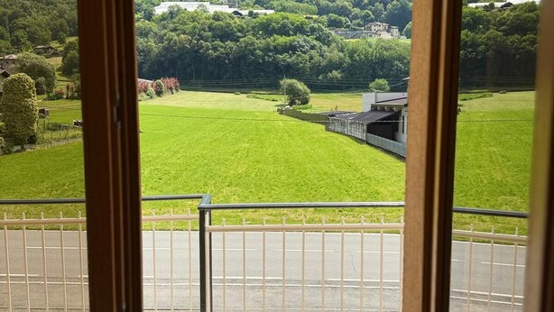A balcony with a view of a green field and forested hills. - At the foot of the Mortirolo (Mazzo di Valtellina)