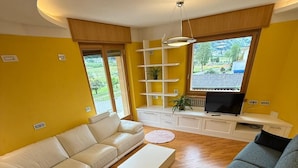 A living room with a white sofa, a grey sofa, a white coffee table, and a TV on a white stand. - At the foot of the Mortirolo (Mazzo di Valtellina)