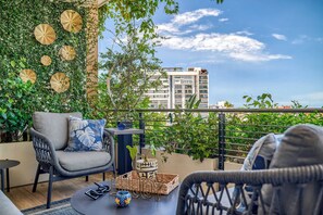 A balcony with wicker furniture, a small table, and a potted plant.