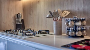 A modern kitchen with a gas stove, stainless steel utensils, and spice jars. - Luxurious Condo at SOHO with Panoramic Romantic Zone Views (Puerto Vallarta)