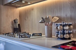 A modern kitchen with a gas stove, stainless steel utensils, and spice jars. - Luxurious Condo at SOHO with Panoramic Romantic Zone Views (Puerto Vallarta)