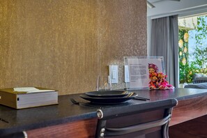 A hotel reception desk with a wooden counter, a glass of water, a menu, and a decorative item. - Luxurious Condo at SOHO with Panoramic Romantic Zone Views (Puerto Vallarta)
