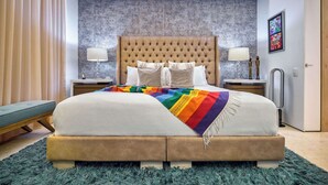 A bedroom with a tufted headboard, a bed with a rainbow-patterned blanket, two bedside tables with lamps, and a blue shaggy rug. - Luxurious Condo at SOHO with Panoramic Romantic Zone Views (Puerto Vallarta)