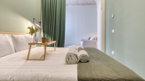 A neatly made bed with a wooden bedside table, a lamp, and a rolled towel.