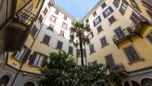 A narrow courtyard with buildings on either side, featuring balconies and windows with shutters.