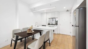 Een moderne keuken met witte kasten, een centraal eiland en een eethoek met een donkere tafel en stoelen.