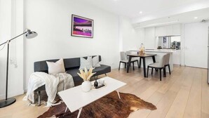 Een moderne woonkamer met een bank, salontafel en een eethoek met stoelen.