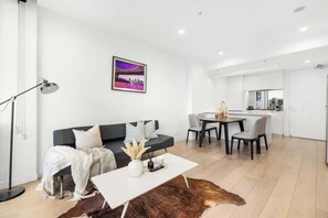 Ein modernes Wohnzimmer mit Sofa, Couchtisch und einem Essbereich mit Stühlen.