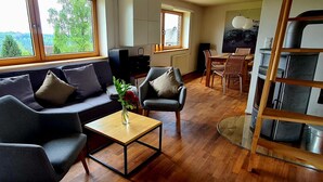 Uma sala de estar com sofá, cadeiras, mesa de centro e um espaço de jantar com mesa e cadeiras.