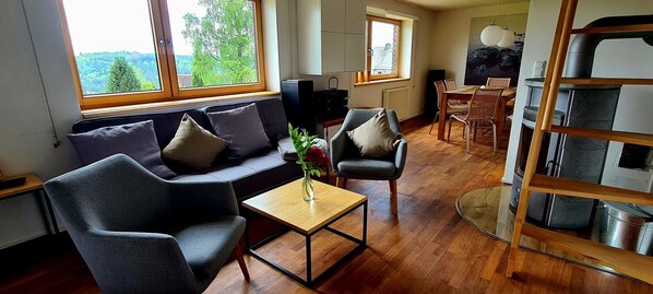 A living room with a sofa, chairs, a coffee table, and a dining area with a table and chairs.