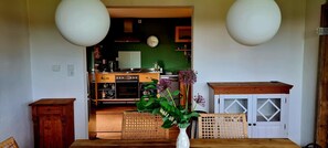 Una cocina con comedor, armarios de madera, un reloj y un florero con flores.
