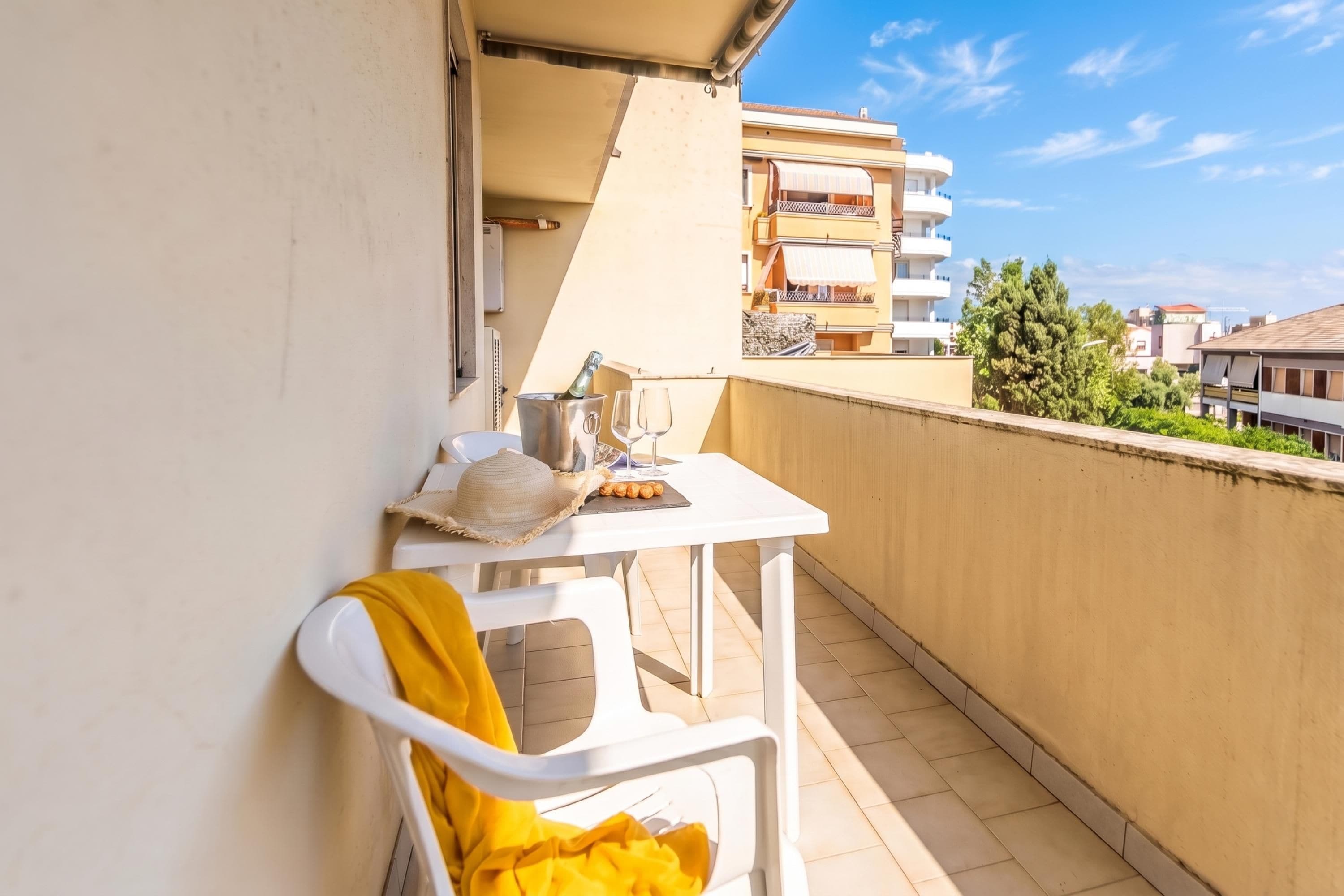 Een balkon met een tafel gedekt voor twee personen, een stoel en een fles champagne.
