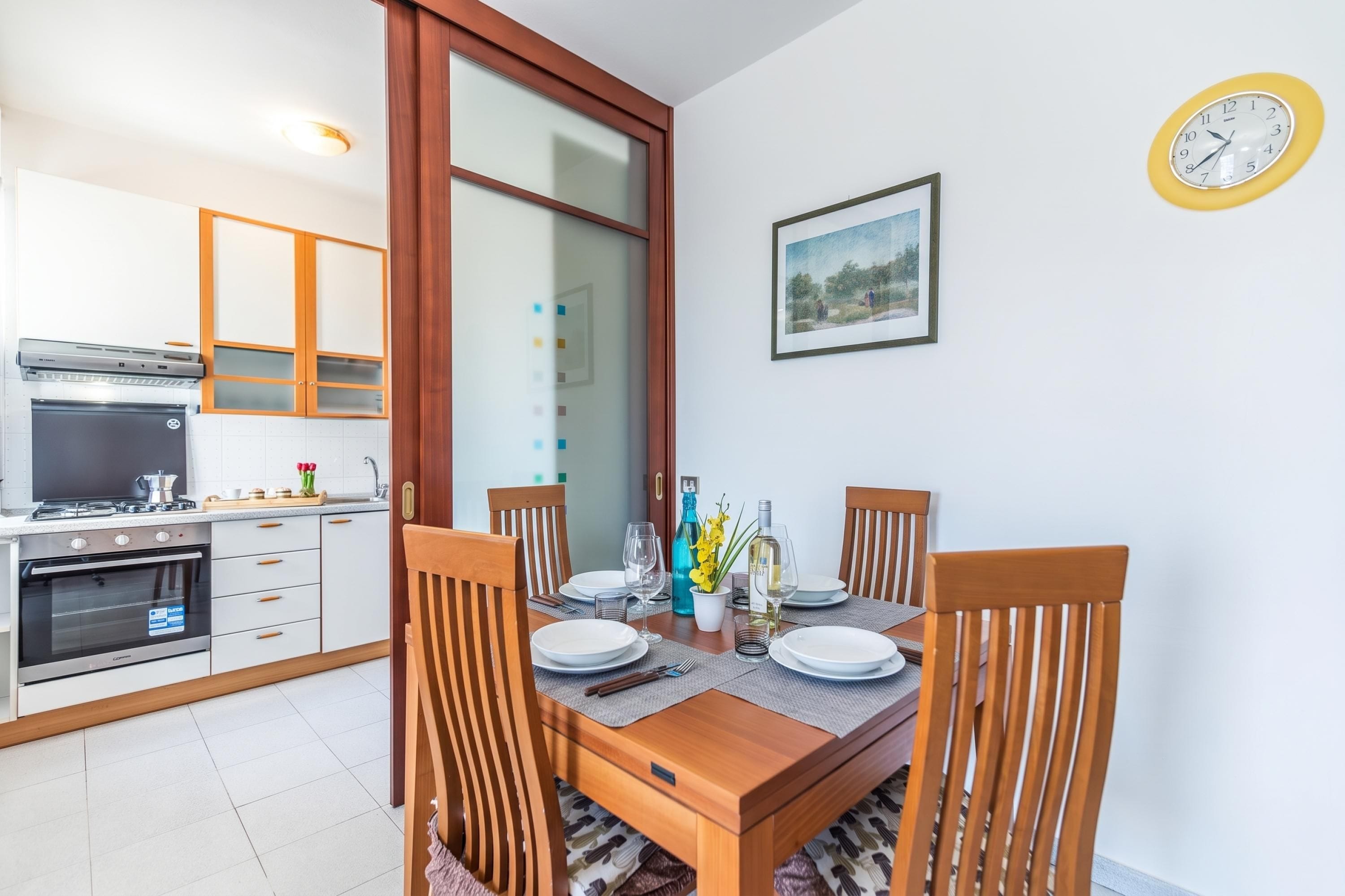 Cozinha moderna com área de jantar, incluindo uma mesa posta para dois, com pratos, copos e talheres.